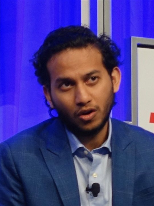 Ritesh Agarwal in a blue jacket speaking on stage